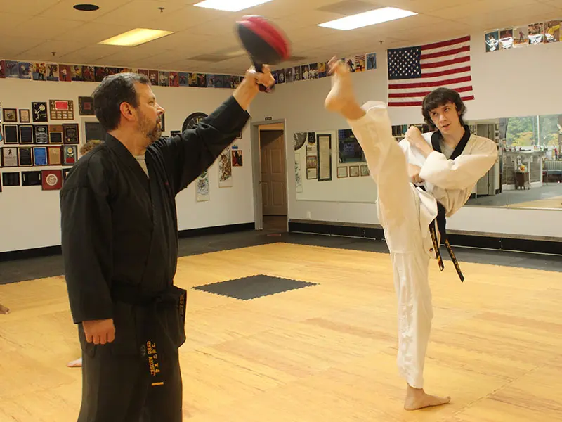 Adult martial arts participants kicking pads during stress-relief workout session